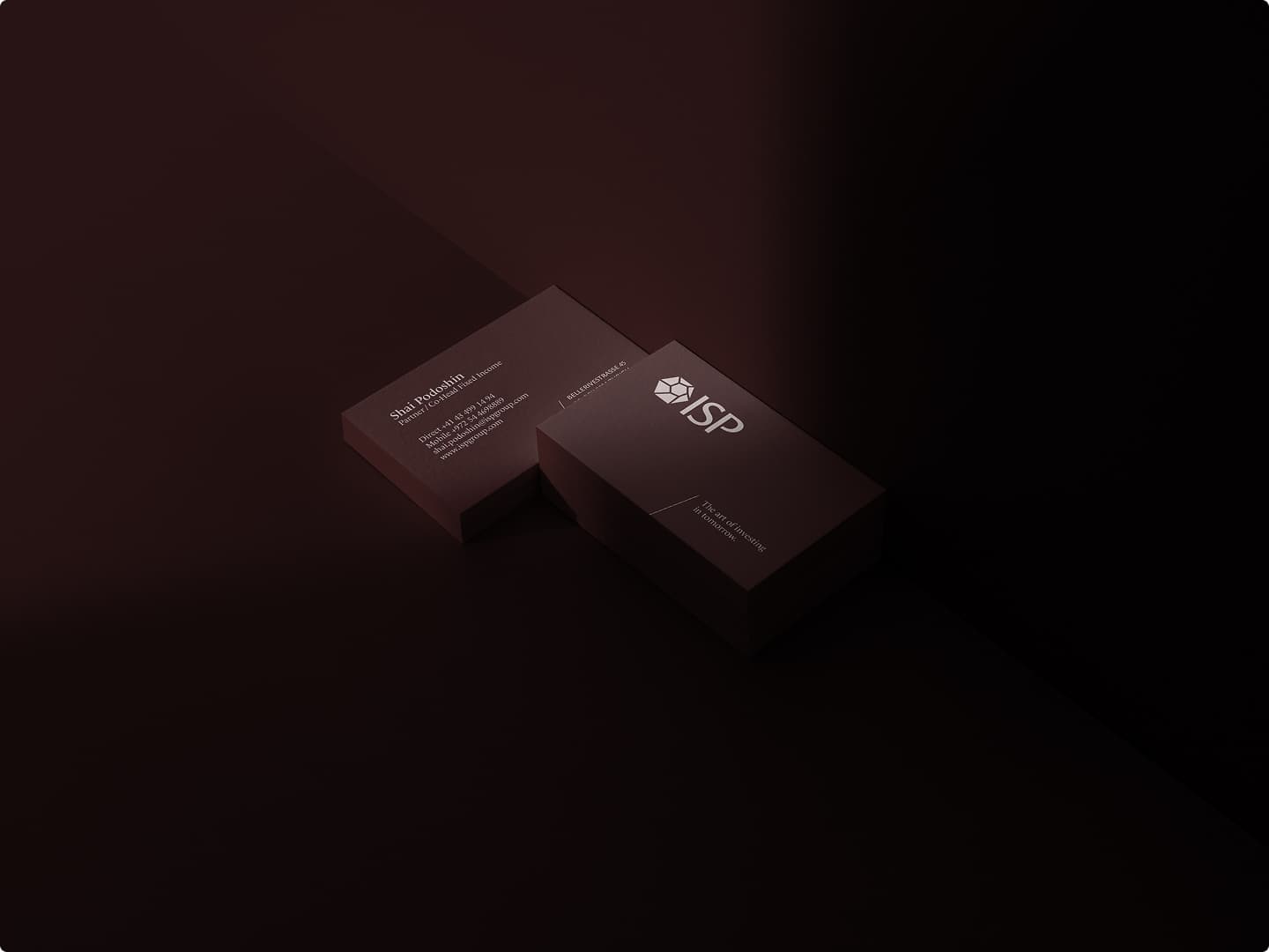 ISP Group business cards with the emblem and wordmark on a dark burgundy surface